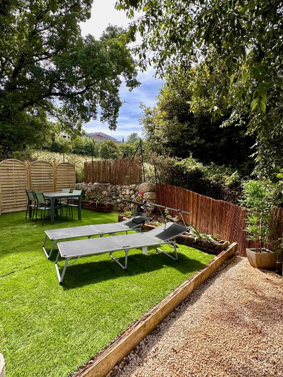 un jardin avec un banc et une table sur la pelouse dans l'établissement Le jardin des senteurs - 2 pièces avec jardin, à Grasse