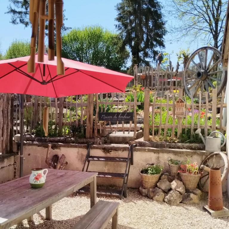 - une table de pique-nique avec un parasol rouge dans le jardin dans l'établissement Au pied du vignoble Champenois, à Cunfin