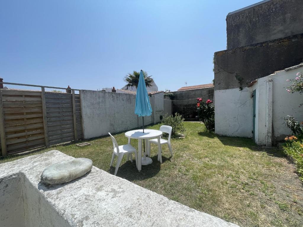 - une terrasse avec une table, 2 chaises et un parasol dans l'établissement La Maison du Marin, à Saint-Gilles-Croix-de-Vie