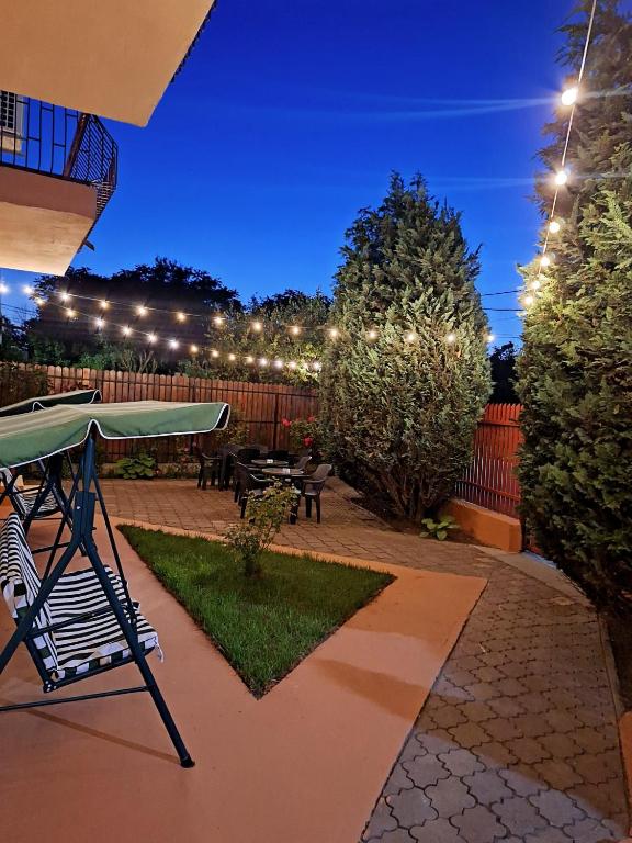 a patio with a table and benches and lights at Vila Tropical in Costinesti