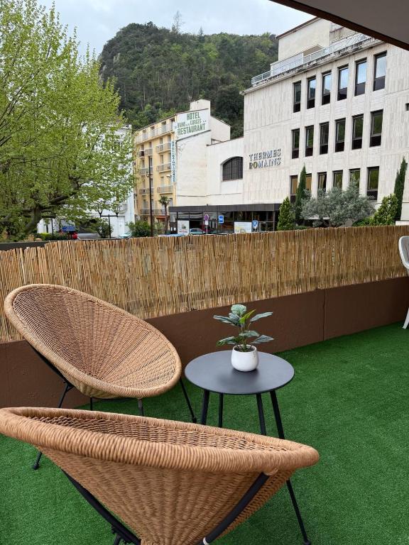 eine Terrasse mit zwei Stühlen und einem Tisch mit einer Topfpflanze in der Unterkunft Studio tout équipé face aux thermes in Amélie-les-Bains-Palalda