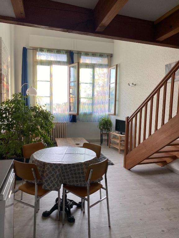 een eetkamer met een tafel en stoelen en een trap bij Appartement Hyper Centre in Limoges