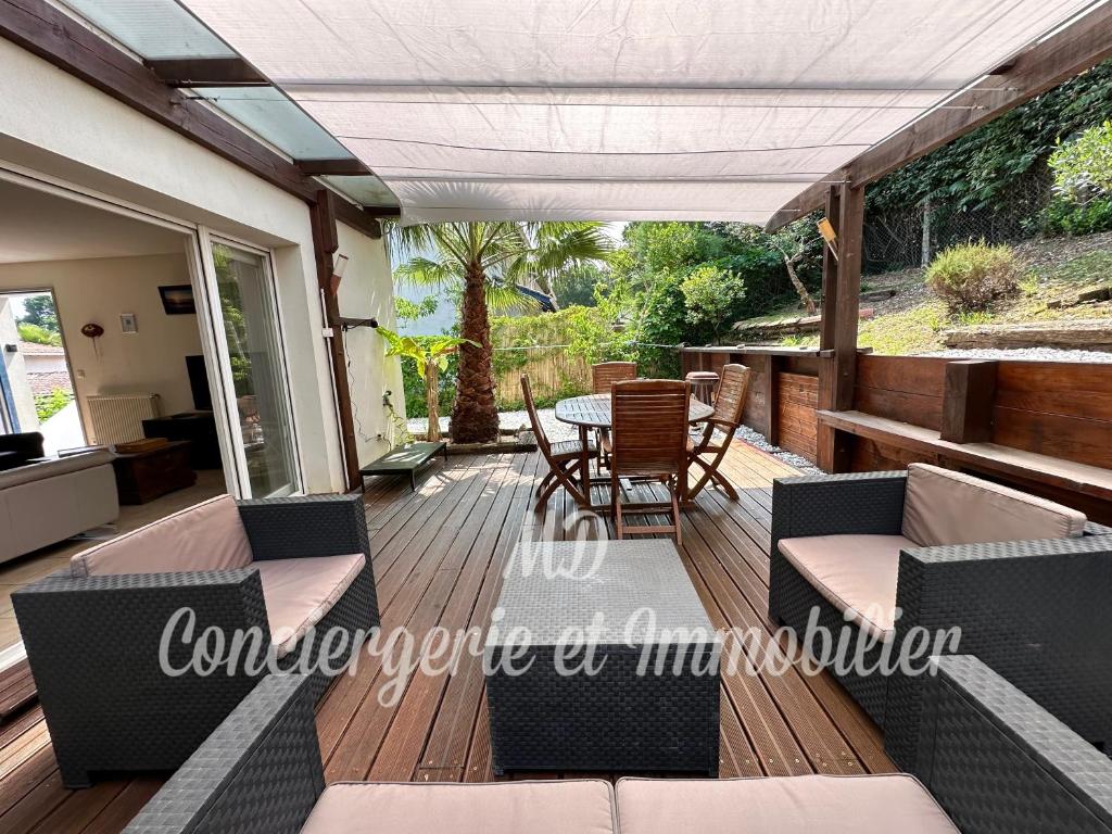 un patio avec une table et des chaises sur une terrasse dans l'établissement Maison avec jardin et parking, à Capbreton