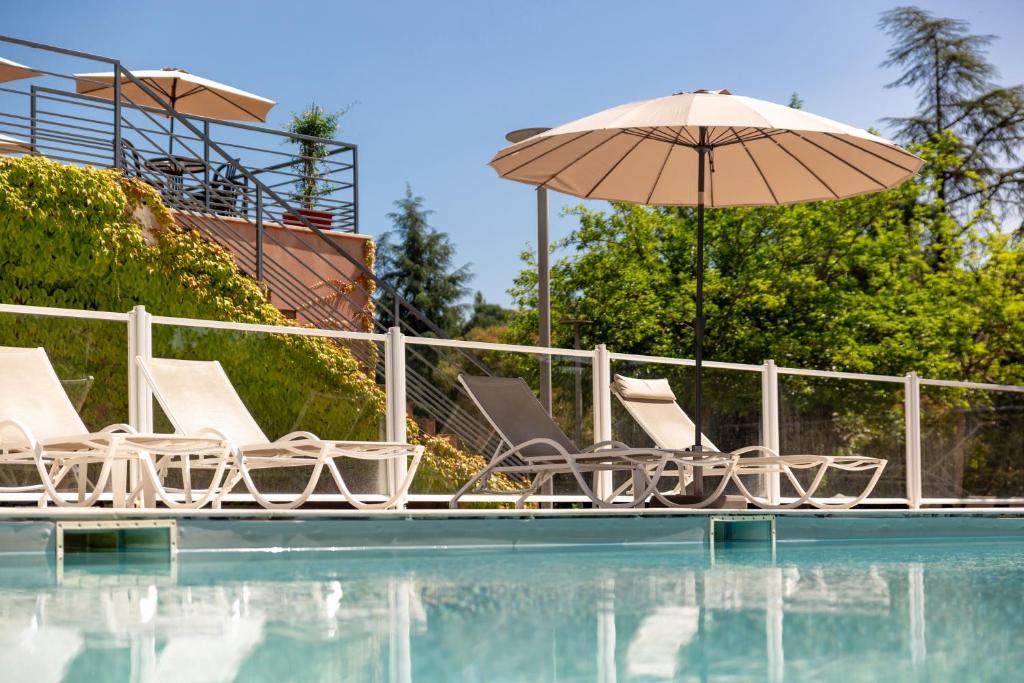 a group of chairs and an umbrella next to a swimming pool at Hôtel & Résidence Lou Paradou Gréoux Les Bains in Gréoux-les-Bains