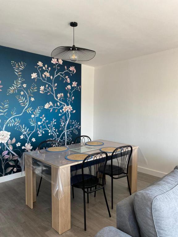 une table à manger avec des chaises et un mur bleu dans l'établissement Appartement T2 renové en 2023, à Lannion