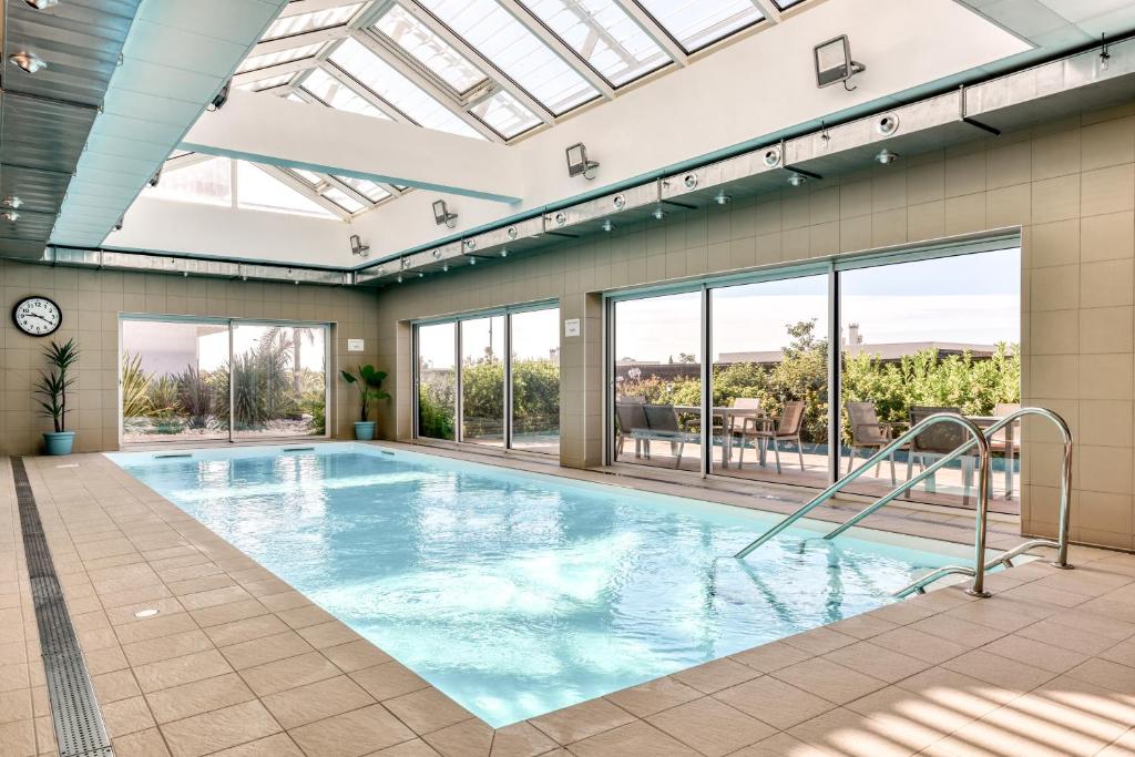 a swimming pool with a skylight in a building at Zenitude Hôtel-Résidences Perpignan in Perpignan