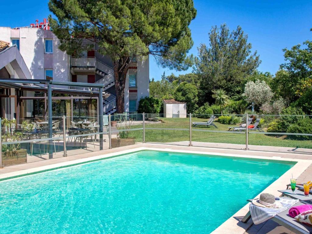 a swimming pool in front of a building at ibis Salon de Provence in Salon-de-Provence