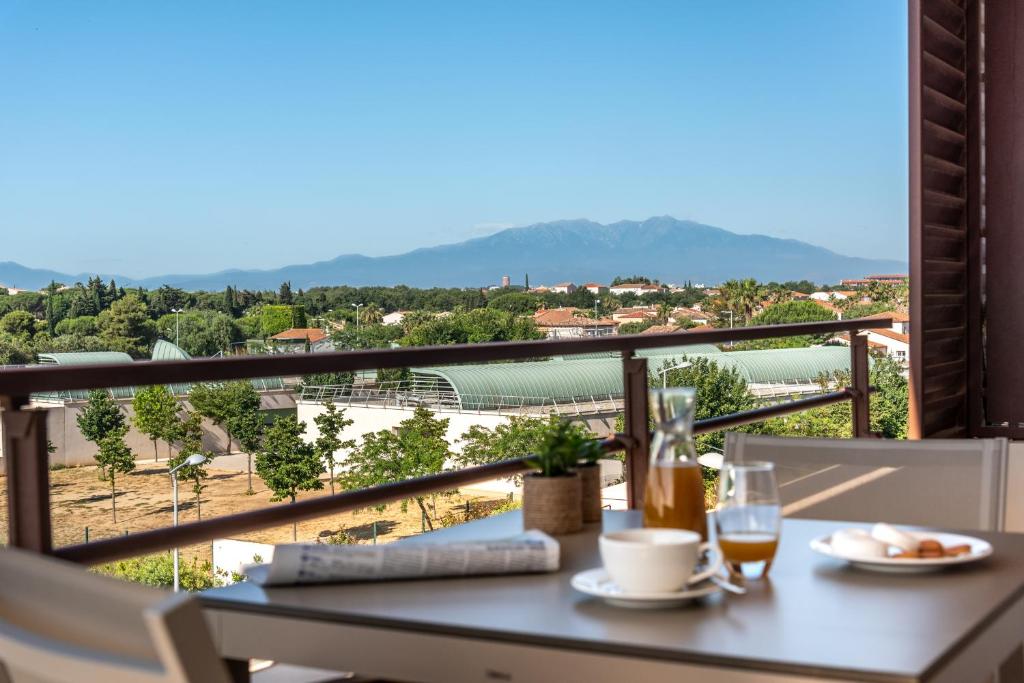 a table with a glass of wine on a balcony at Zenitude Hôtel-Résidences Perpignan in Perpignan