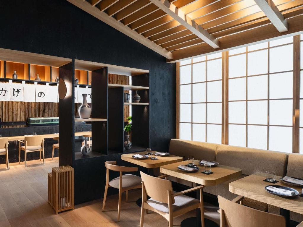 a restaurant with wooden tables and chairs and windows at Sofitel Casablanca Tour Blanche in Casablanca