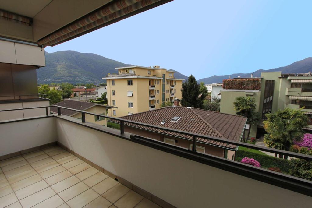 een balkon met uitzicht op enkele gebouwen en bergen bij Alle Vigne, 3 Stock by HolAp SA in Ascona