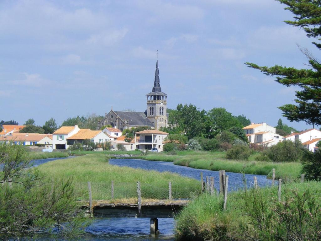 eine Brücke über einen Fluss mit einer Kirche im Hintergrund in der Unterkunft Chevrefeuille et Eglantine in LʼÎle-dʼOlonne