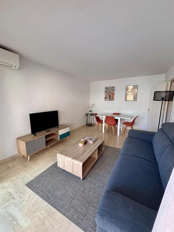 un salon avec un canapé bleu et une table dans l'établissement Appartement proche de la plage et du centre ville, à Sainte-Maxime