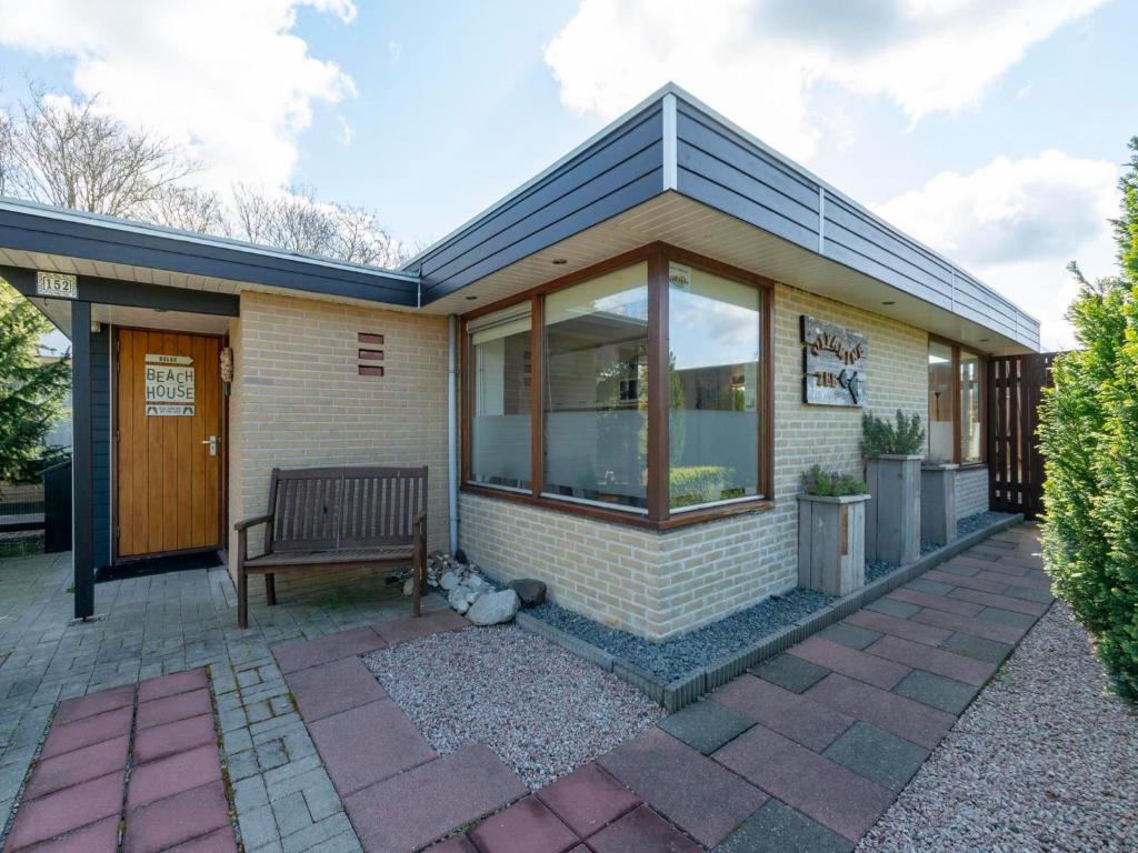 a house with a bench on a patio at Holiday Home Sint Maartenszee near Beach in Sint Maartensvlotbrug