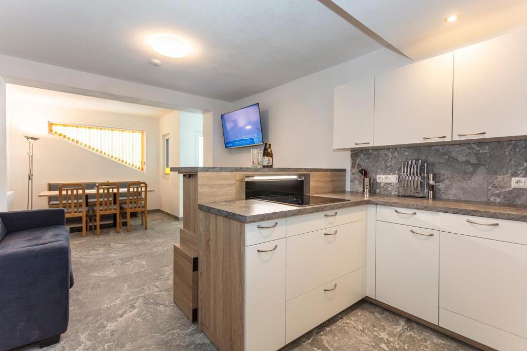 a kitchen with white cabinets and a dining room at Sonnige Ruhe in Embach
