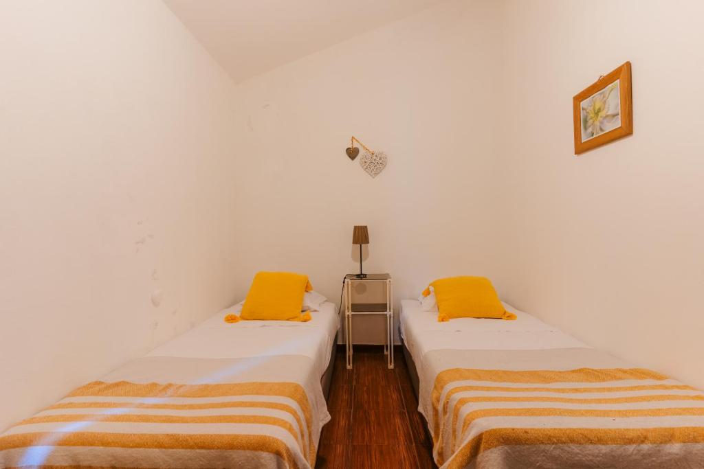 zwei Betten in einem Zimmer mit weißen Wänden und gelben Kissen in der Unterkunft Apartamento 2 - Fundação de Veiros in Veiros