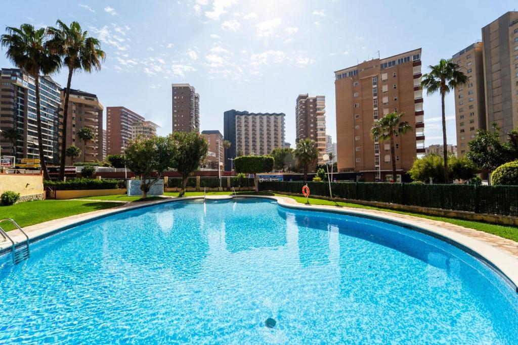 a large swimming pool in a city with tall buildings at Stylish Seaview Apartment with Pool Access in Benidorm
