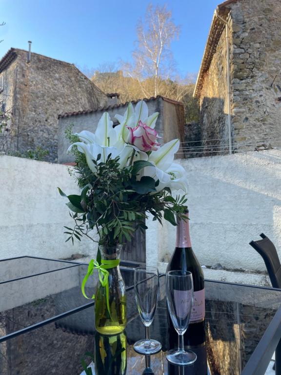 une bouteille de vin avec un bouquet de fleurs et deux verres dans l'établissement Maison Bleu, à Puilaurens