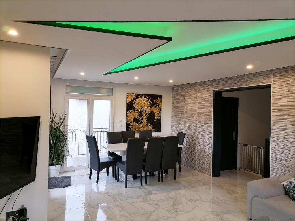 une salle à manger avec une table, des chaises et une lumière verte dans l'établissement Maison spacieuse très calme, Albi centre, à Albi