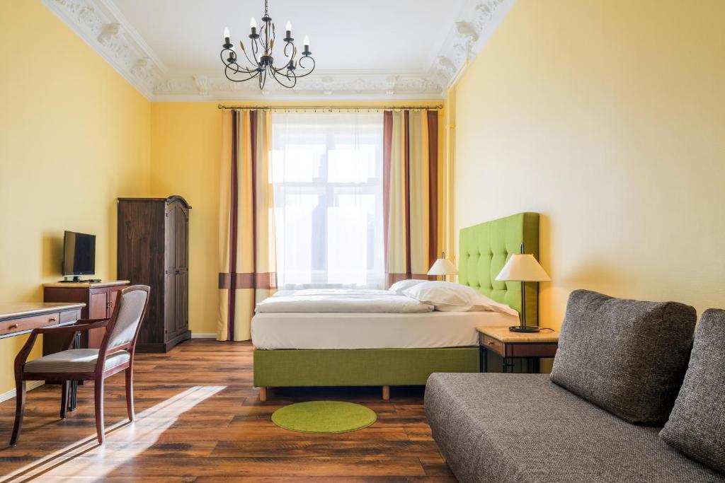 a bedroom with a bed and a desk and a couch at Hotel-Pension Michele in Berlin