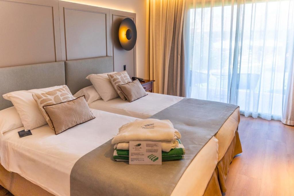 two beds in a hotel room with boxes on them at La Quinta Menorca by PortBlue Boutique - Adults Only in Cala'n Bosch
