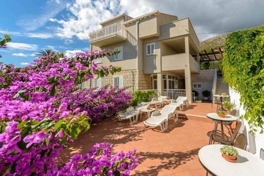 un complejo con flores púrpuras, mesas y sillas en Apartments Nina&Anita, en Dubrovnik