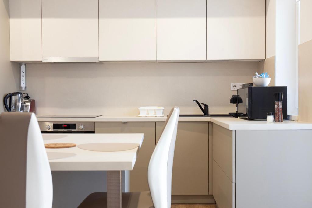 a kitchen with white cabinets and a white table and chairs at Luxus Apartman in Nyíregyháza