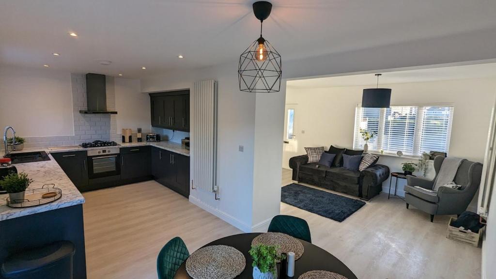 eine Küche und ein Wohnzimmer mit einer Couch und einem Tisch in der Unterkunft Modern Gilliver House Rural retreat sleeps 7 in Barlestone