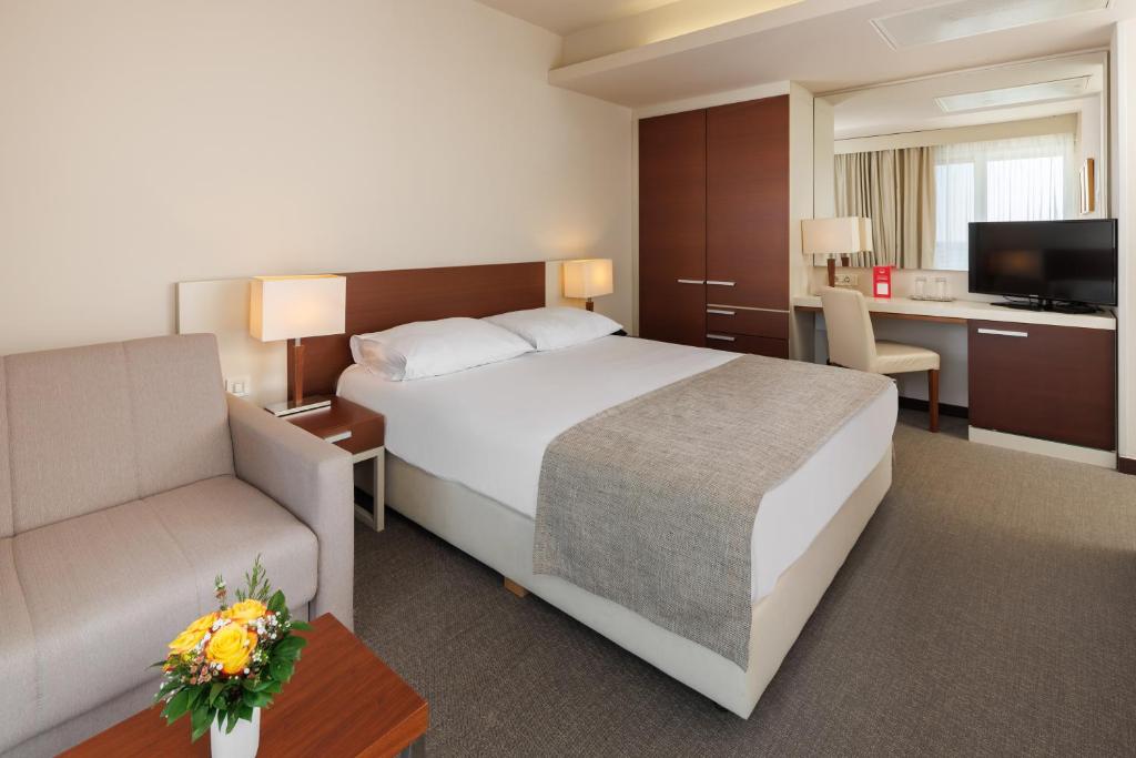 a hotel room with a large bed and a desk at Hotel Albatros Plava Laguna in Poreč