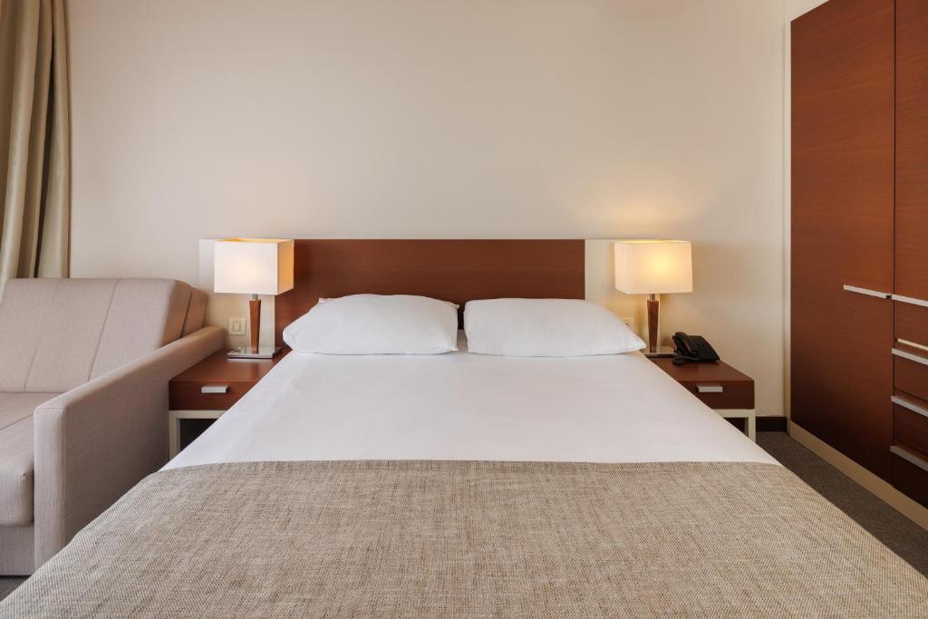 a bedroom with a large white bed with two lamps at Hotel Albatros Plava Laguna in Poreč