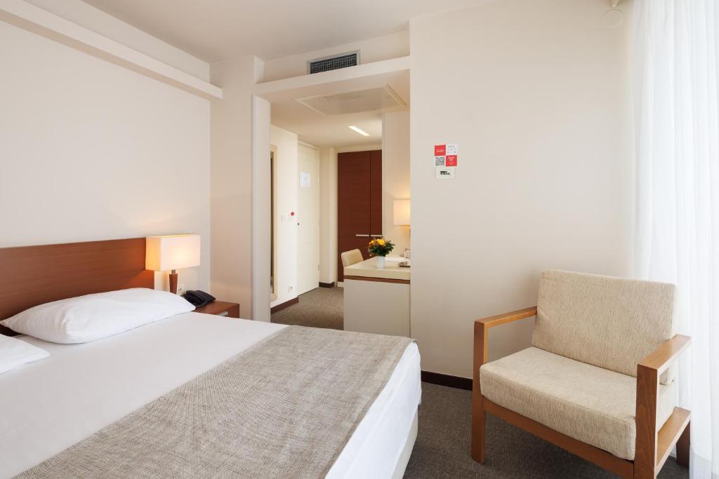a hotel room with a bed and a chair at Hotel Albatros Plava Laguna in Poreč