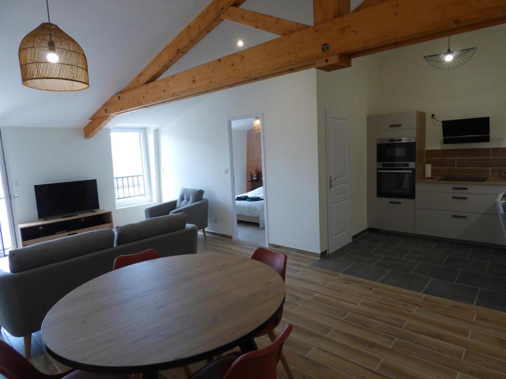 a living room with a wooden table and a kitchen at Les Frères Caudron, appartement centre ville in Le Crotoy