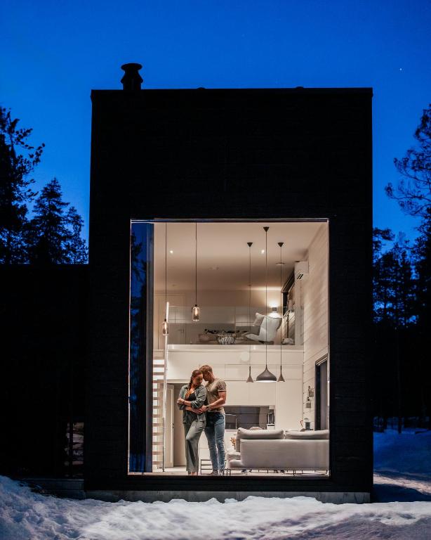 two people standing in a window of a house at Polaris Villas - Villa BLÄKK in Muonio
