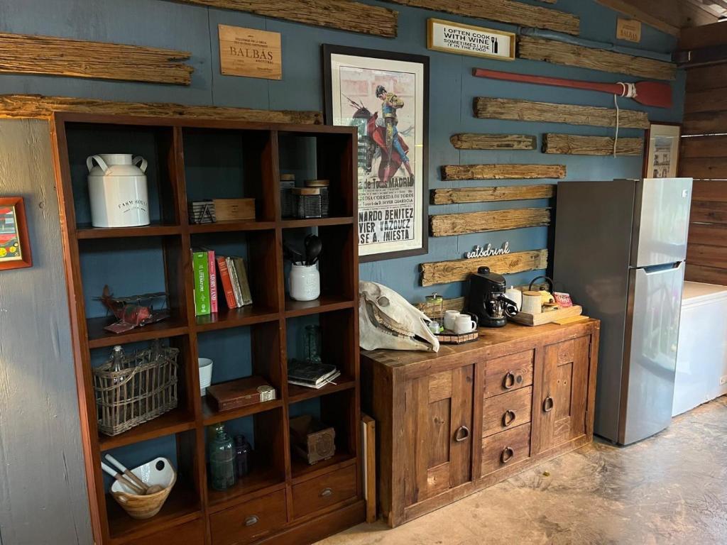 cocina con nevera y estante para libros en Rustic cabin in the heart of the fields of Pitahaya, en Cabo Rojo