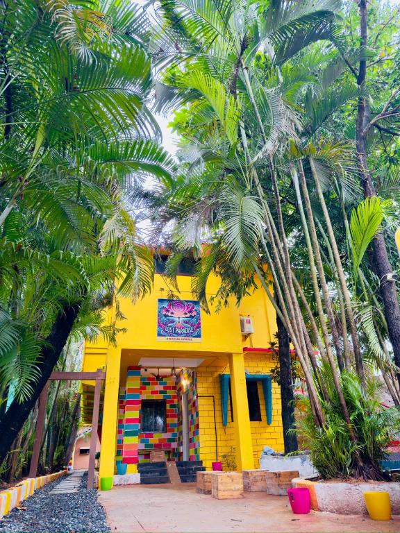 a yellow building with palm trees in front of it at Paradise A Social Hostel in Anjuna