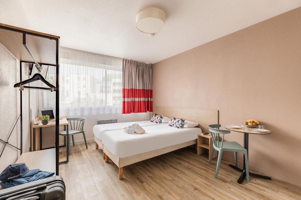 une chambre d'hôtel avec un lit, une table et des chaises dans l'établissement Appart'City Classic La Rochelle Centre, à La Rochelle