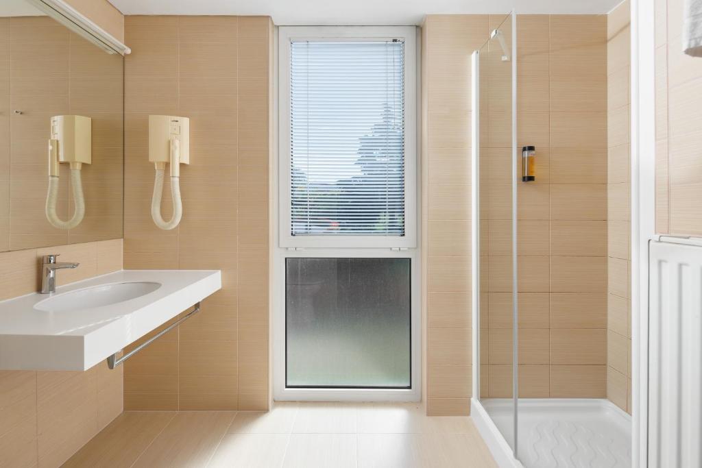a bathroom with a sink and a glass shower at Hotel Albatros Plava Laguna in Poreč