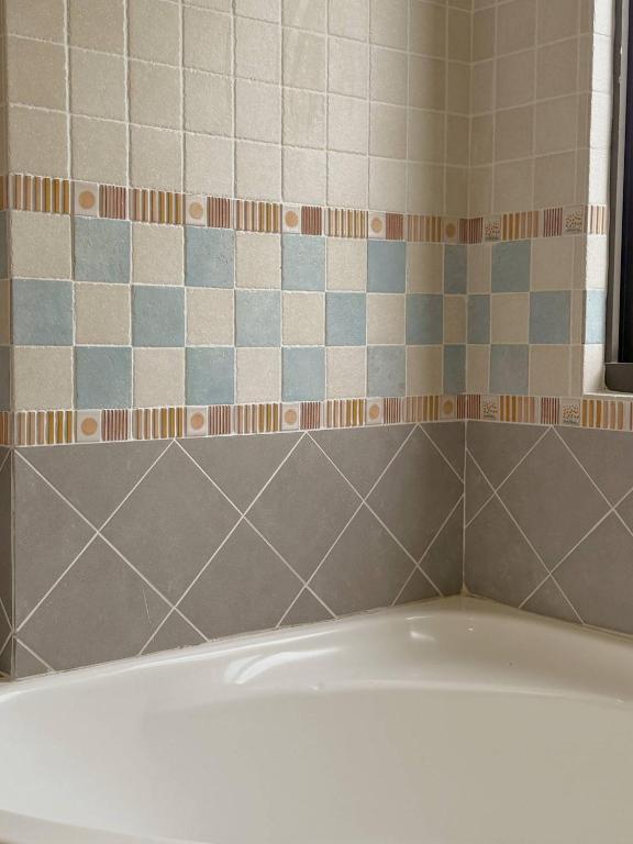 a bathroom with a tub and a tiled wall at E-Ping Castle Hotel in Nanwan