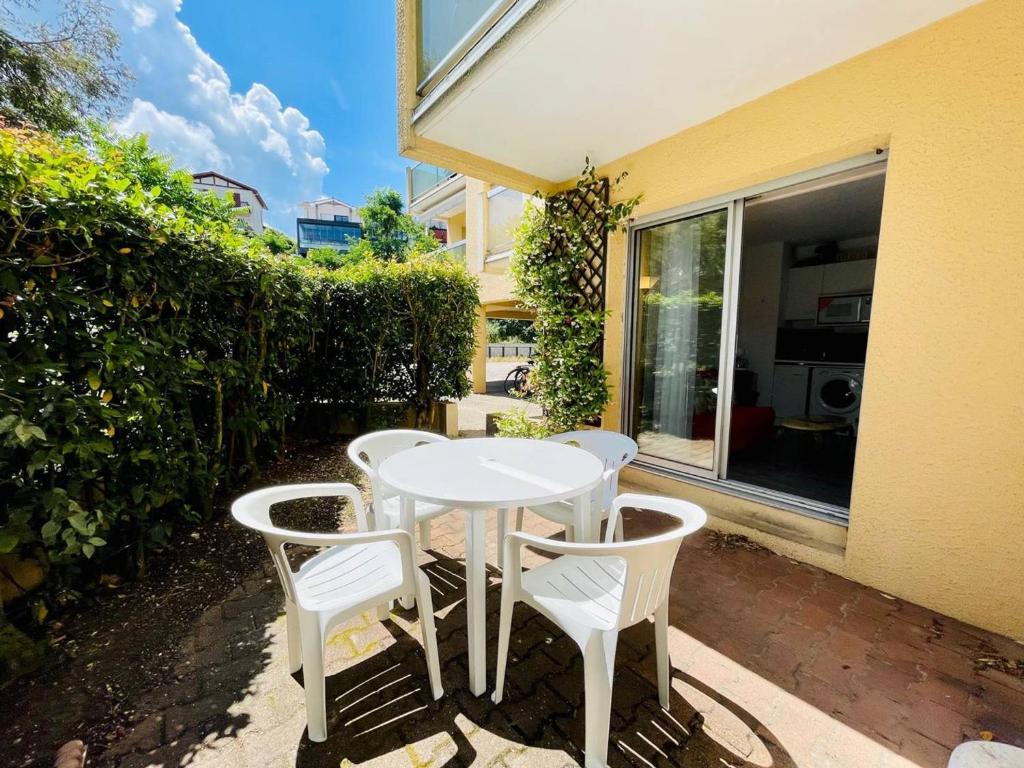 une table blanche et quatre chaises sur la terrasse dans l'établissement Appartement T2 avec terrasse et parking à 100m de la plage d'Eyrac - Arcachon - FR-1-433-13, à Arcachon