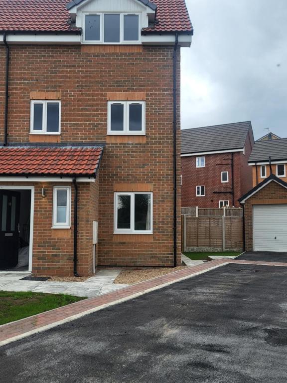 a brick house with a driveway in front of it at Modern 3-Bed House in Rotherham, WiFi, Garden & Free Parking in Kimberworth
