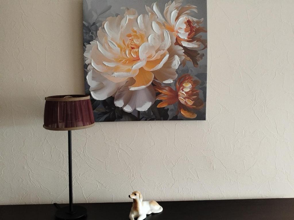 a painting of a flower on a wall next to a lamp at FourSpace in Ventspils