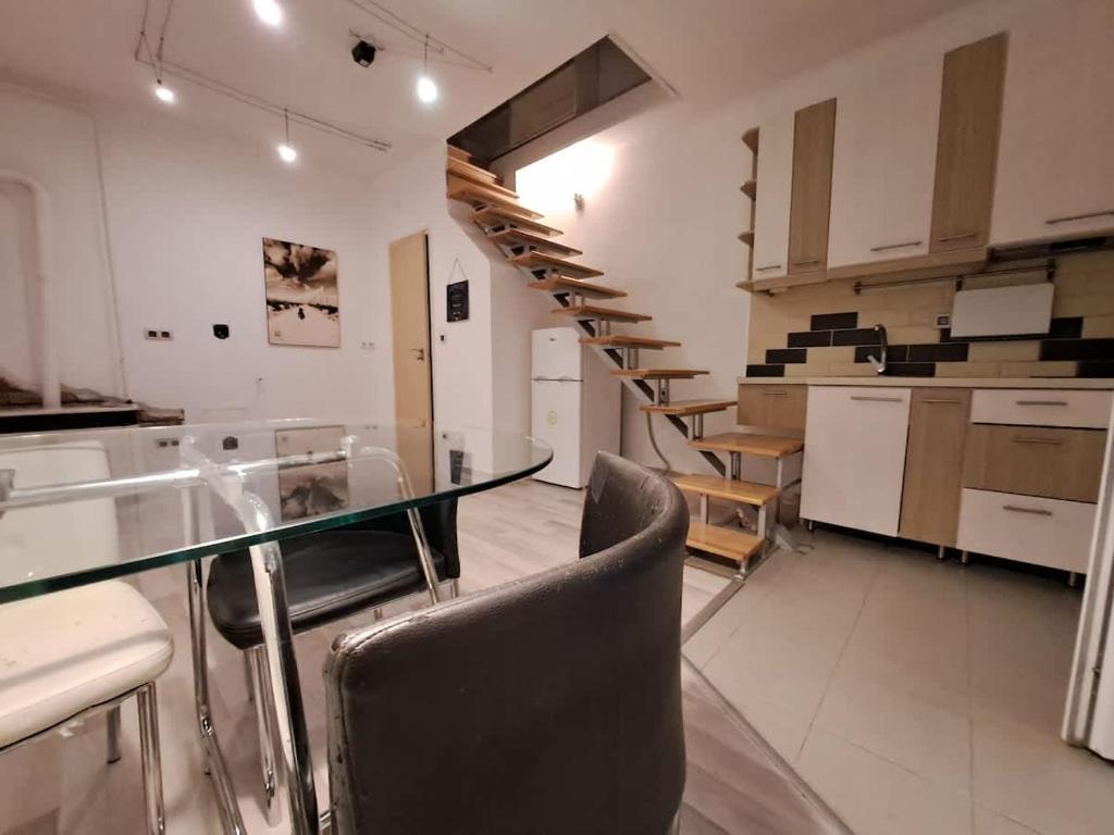 a kitchen with a glass table and chairs and stairs at B42 Cozy in Budapest