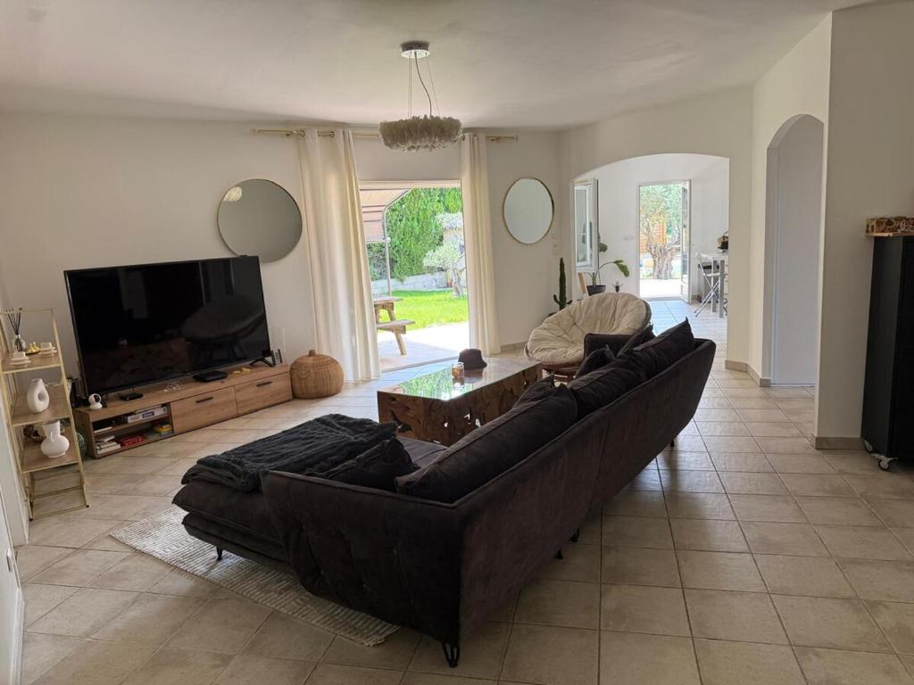 un salon avec un canapé et une télévision à écran plat dans l'établissement Villa du Soleil, à Caveirac