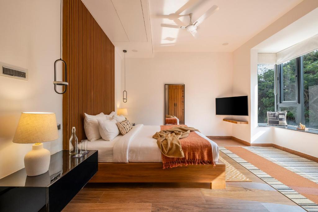 a bedroom with a large bed and a window at SaffronStays Miami in Nerul