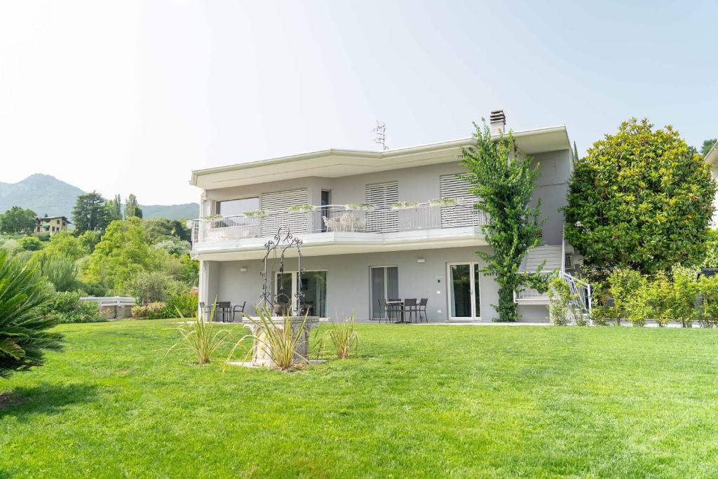 a white house with a lawn in front of it at Holiday Apartments Campoverde in Salò