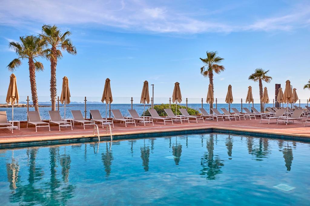 basen z krzesłami, palmami i oceanem w obiekcie Universal Hotel Romantica w miejscowości Colonia Sant Jordi