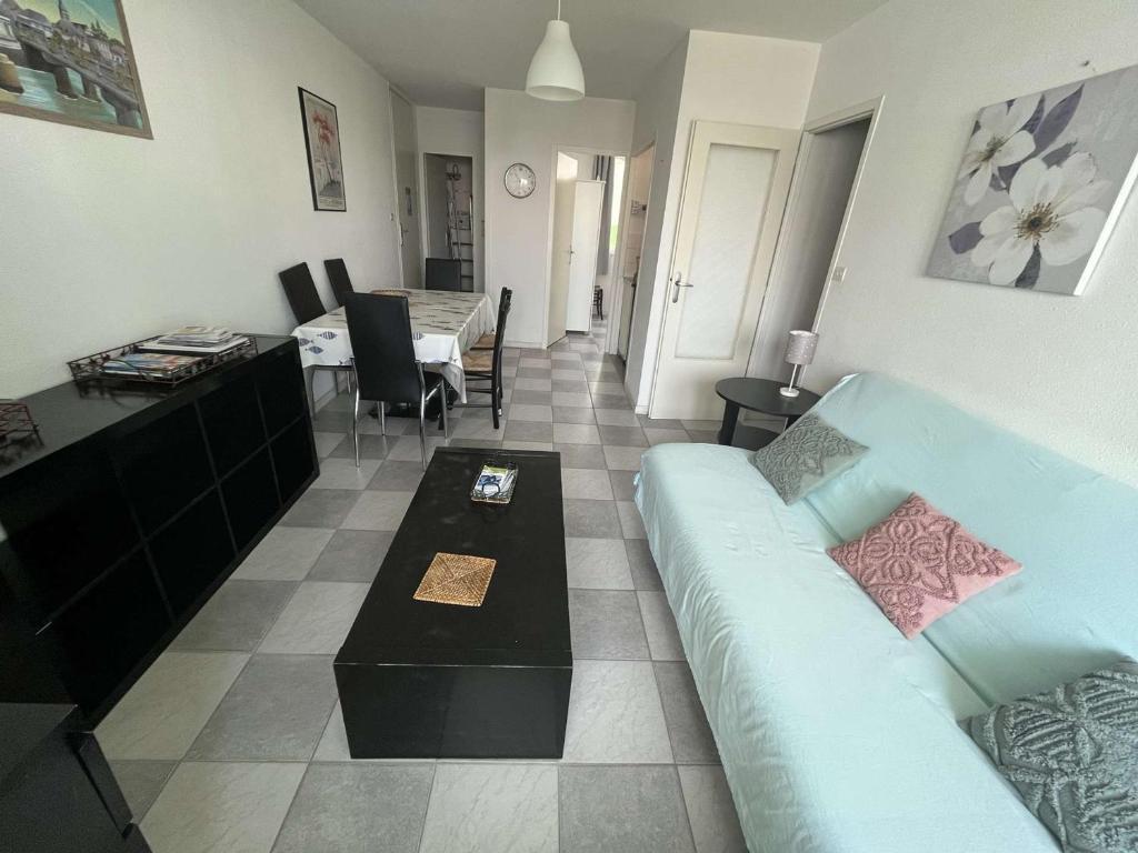 un salon avec un canapé bleu et une table dans l'établissement Charmant T3 en bord de mer, parking privé, animaux admis, non-fumeurs, proche commerces et pistes cyclables - FR-1-324A-59, à Saint-Hilaire-de-Riez