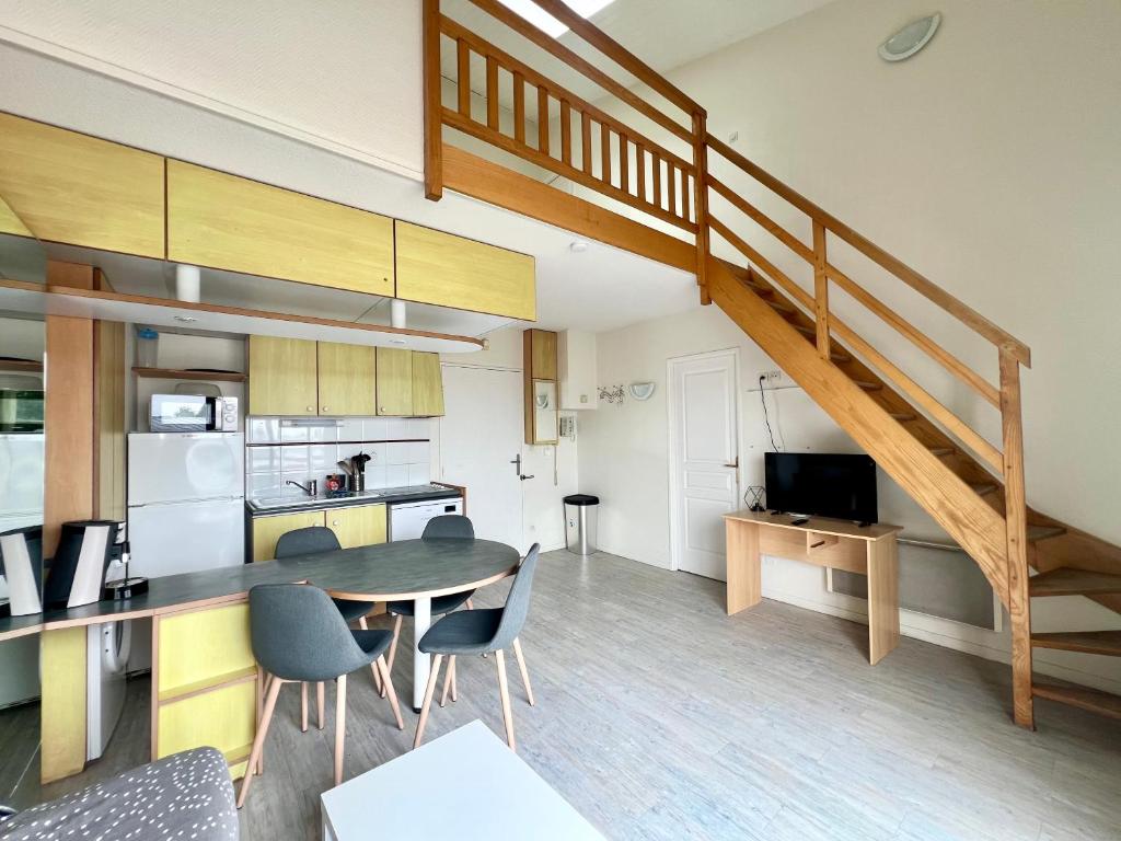 Una cocina y un comedor con una mesa y una escalera. en Apartment with Balcony & Pool in La Rochelle, en La Rochelle