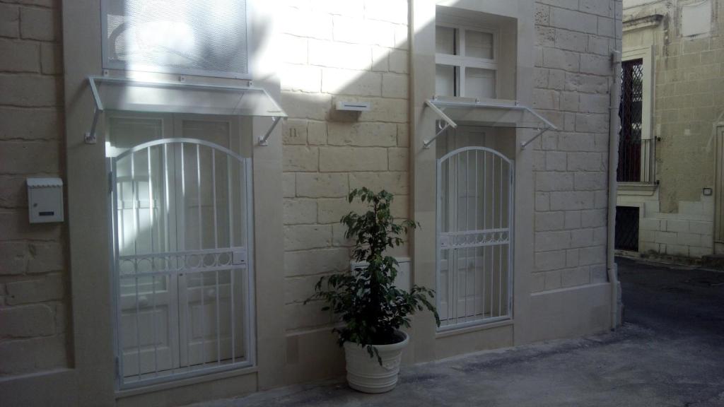 ein Gebäude mit weißen Toren und einer Pflanze in einem Topf in der Unterkunft Casa Anna in Lecce