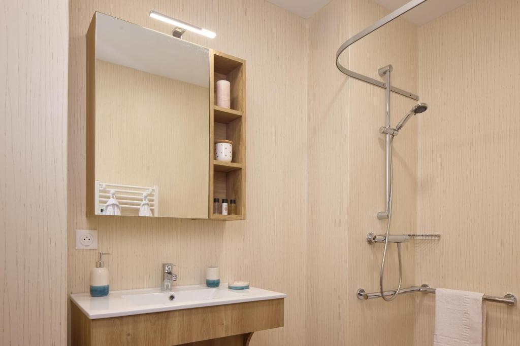 a bathroom with a sink and a mirror and a shower at Zenitude Hôtel-Résidences Le Havre Les Docks in Le Havre