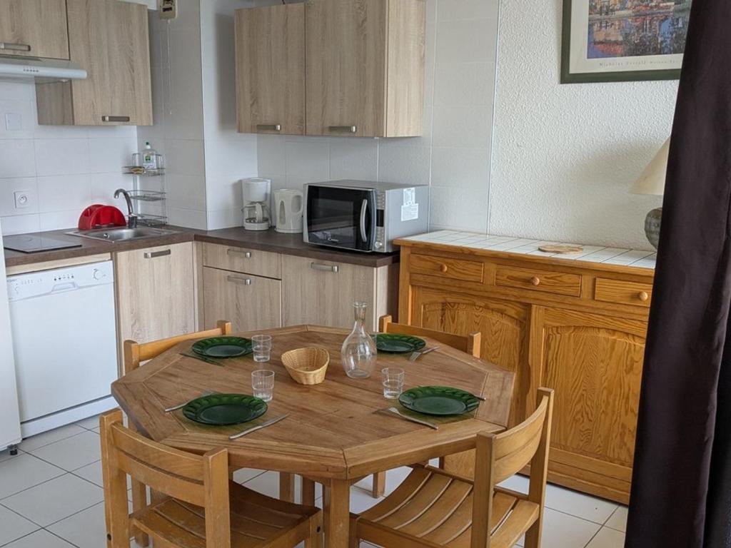 une cuisine avec une table en bois avec quatre chaises et une table dans l'établissement Appartement lumineux 3 pièces 8 pers, proche des pistes avec cuisine équipée - FR-1-262-73, à Forest des Baniols
